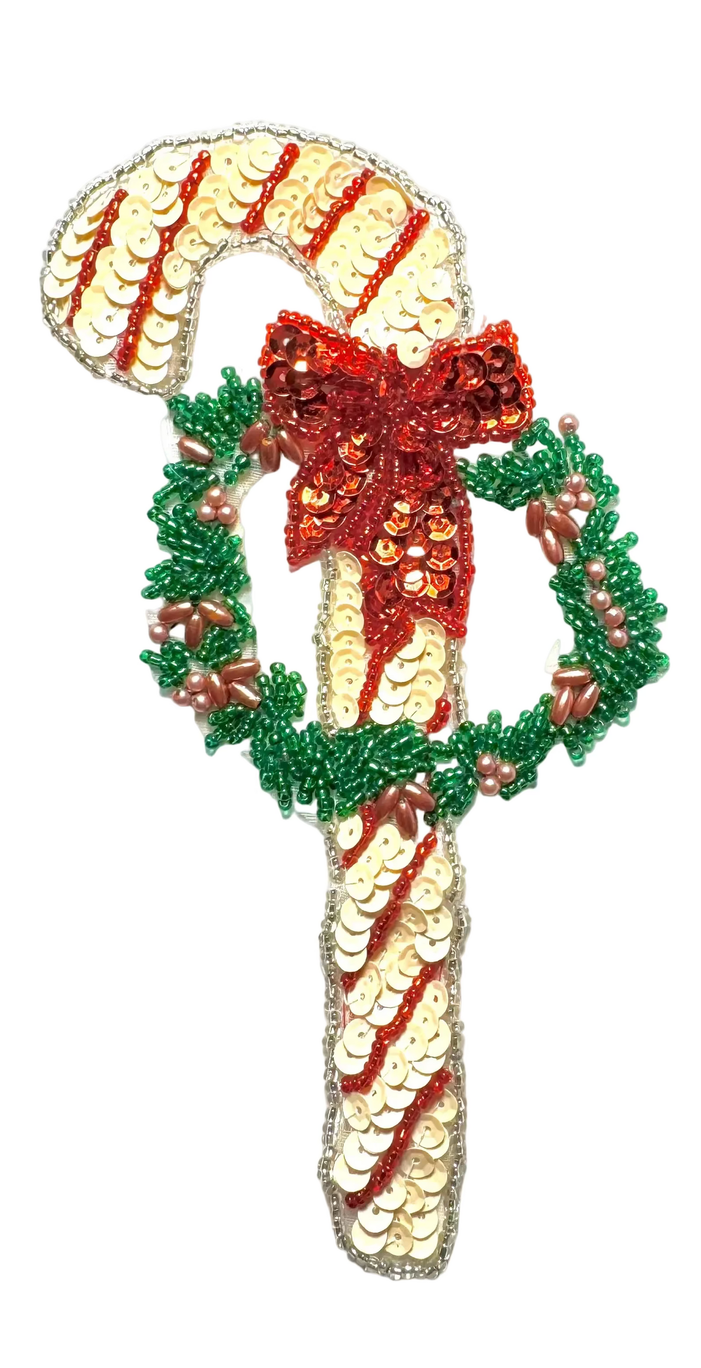 Decorative candy cane with sequins, a red bow, and greenery on a white background
