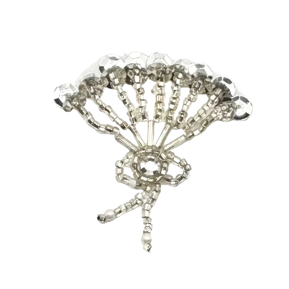 A silver sequin fan featuring a fan-shaped arrangement of silver sequins and beads with a rhinestone and beadwork on a plain white background.