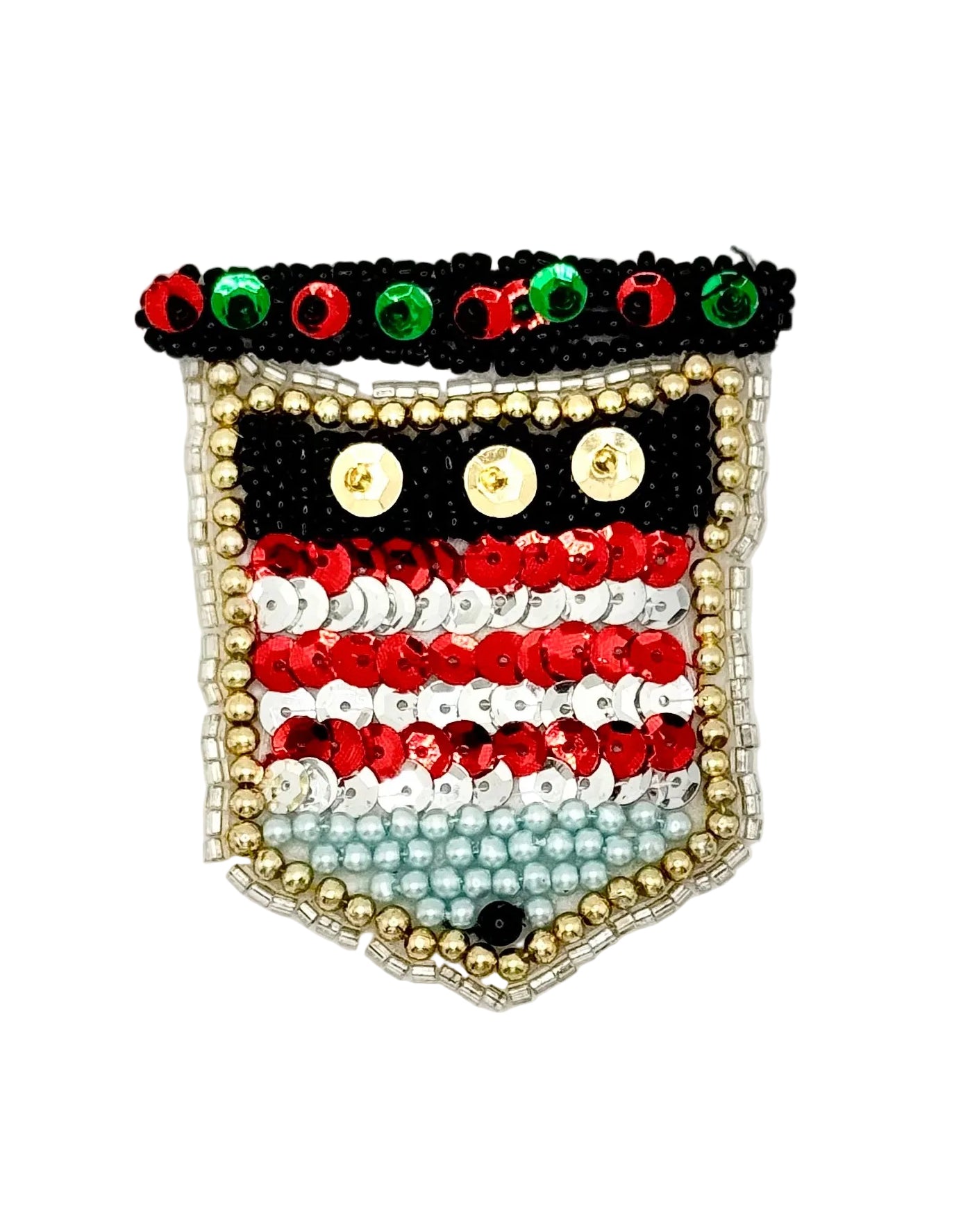 A decorative shield-shaped beaded patch featuring horizontal stripes in black, red, white, and light blue, with gold bead borders and red and green sequins along the top.