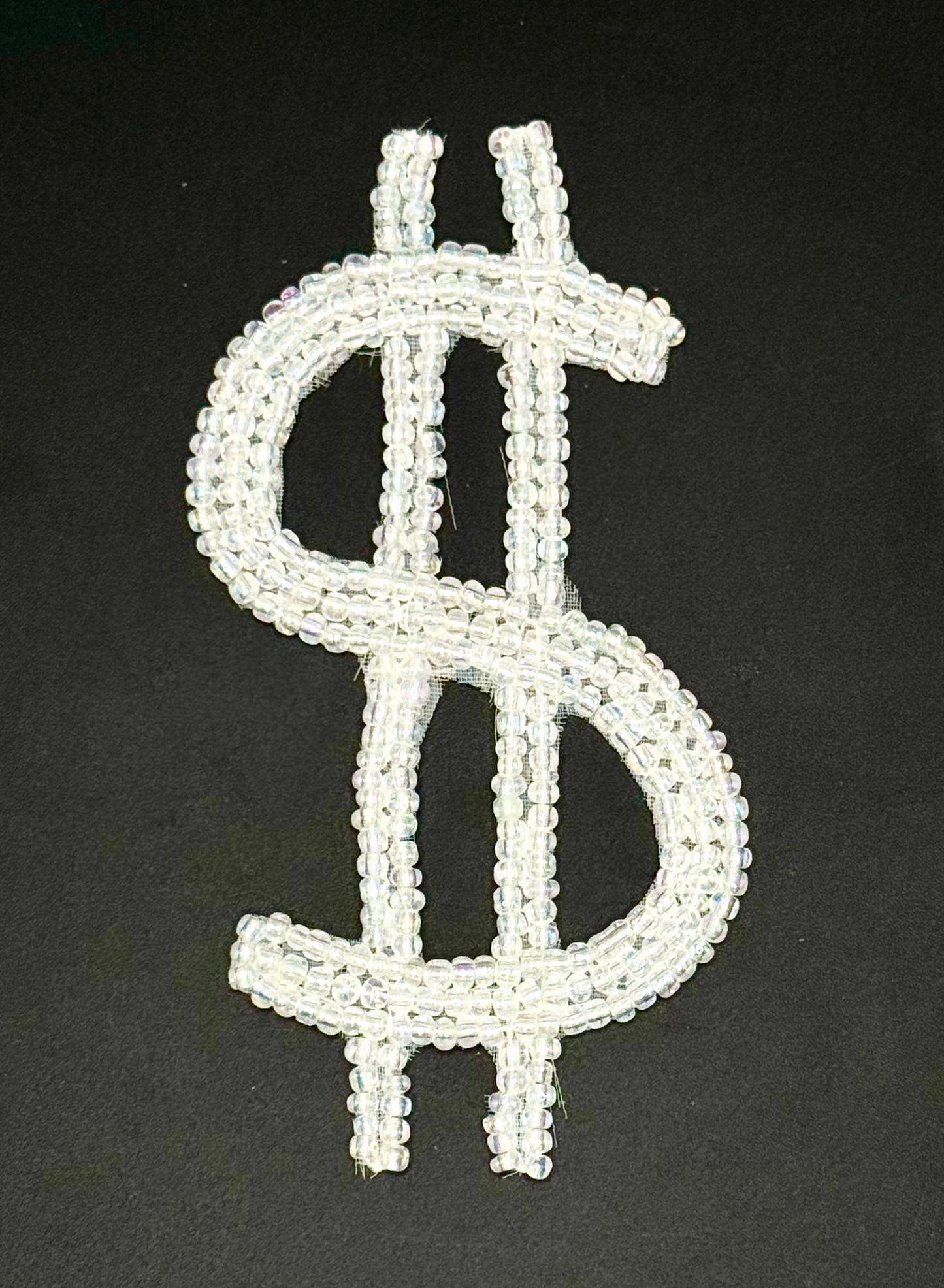 Dollar sign symbol made of white beads on a black background