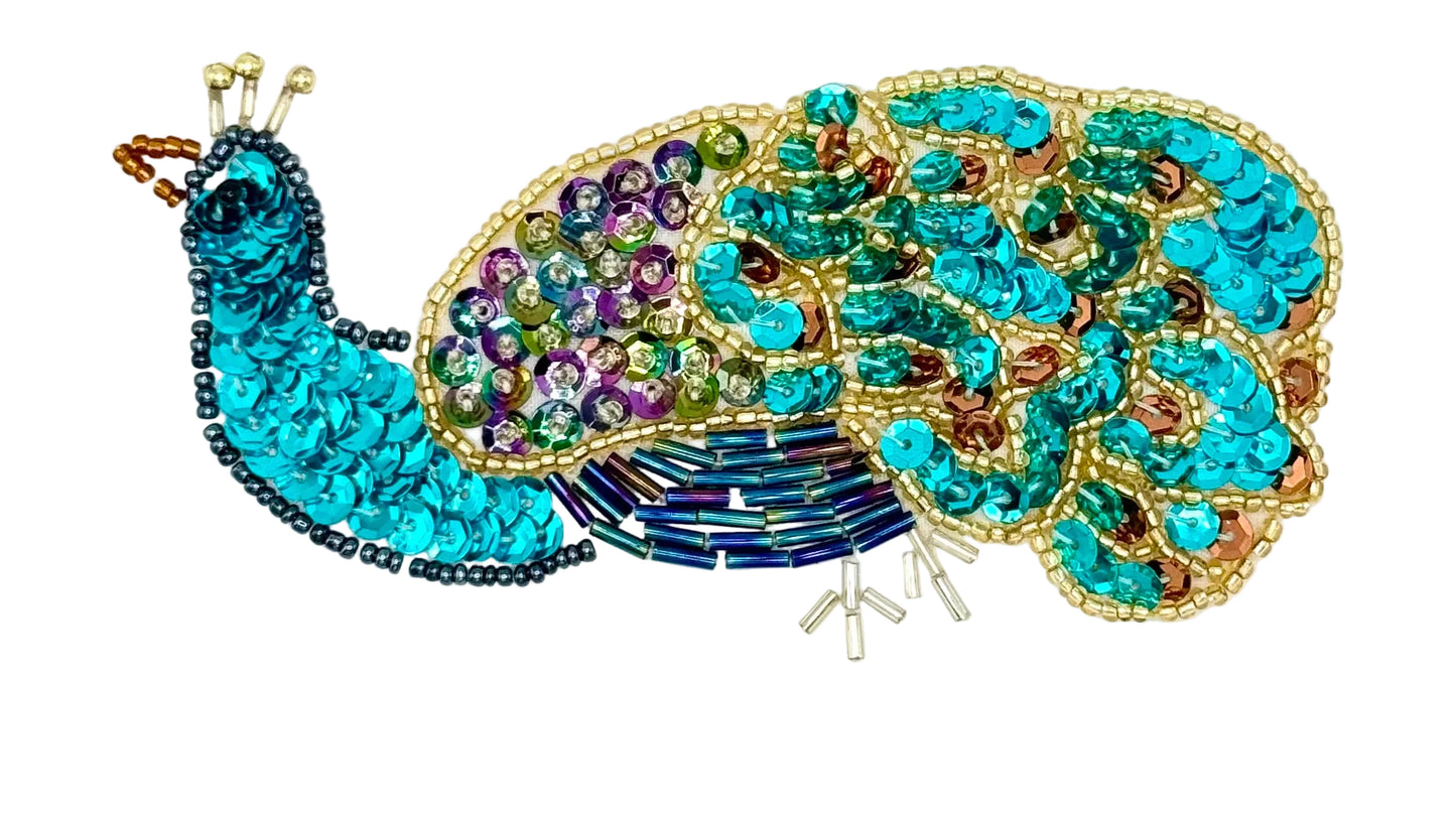 Decorative peacock-shaped sequin patch with colorful beads on a white background
