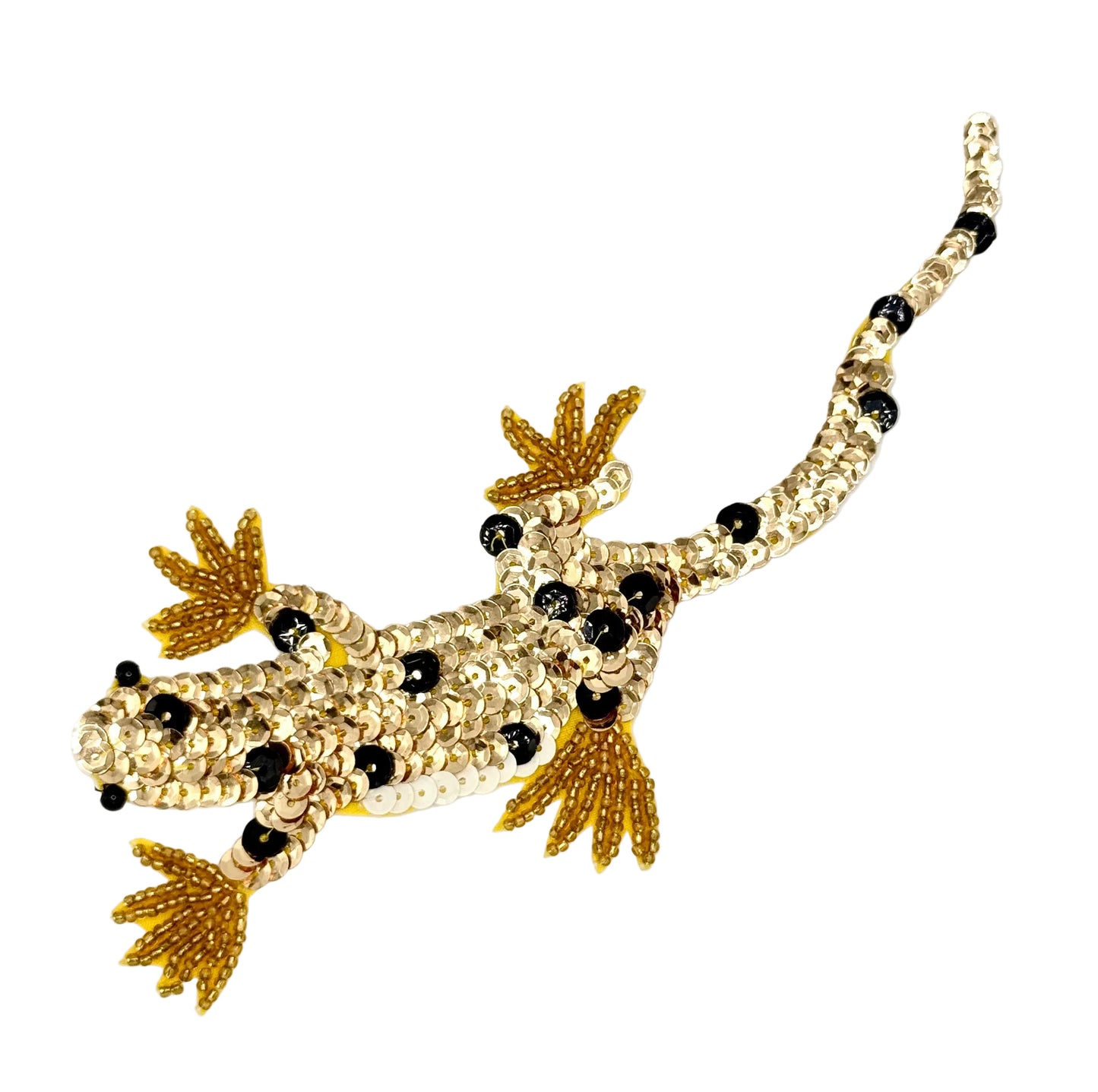 Decorative lizard-shaped animal with gold and black sequins on a white background