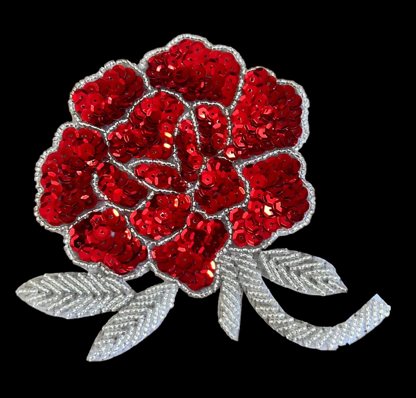 Red sequin rose with silver leaves on a brown background