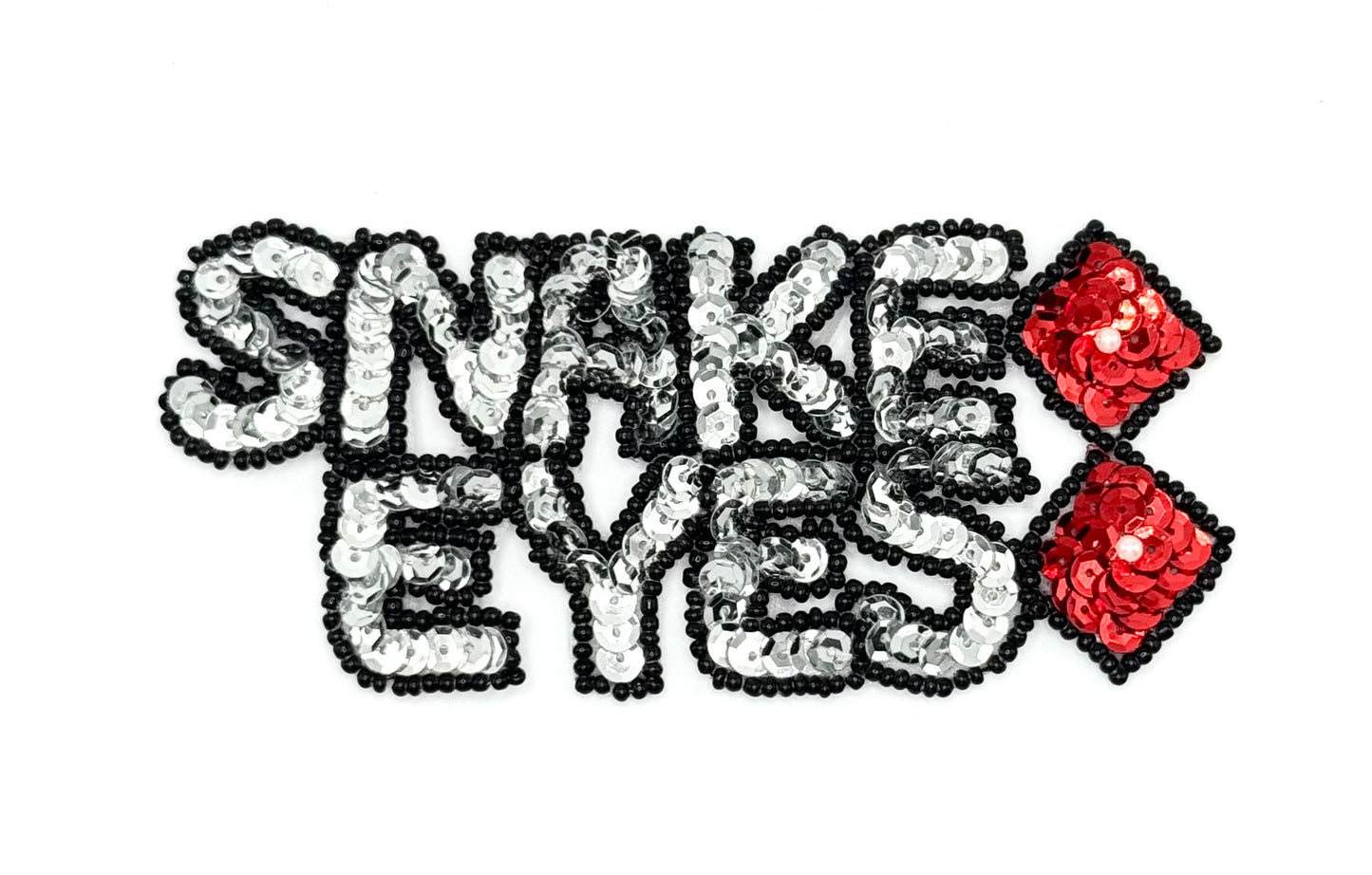 The words Snake Eyes in sequins and beads with dice on a white background