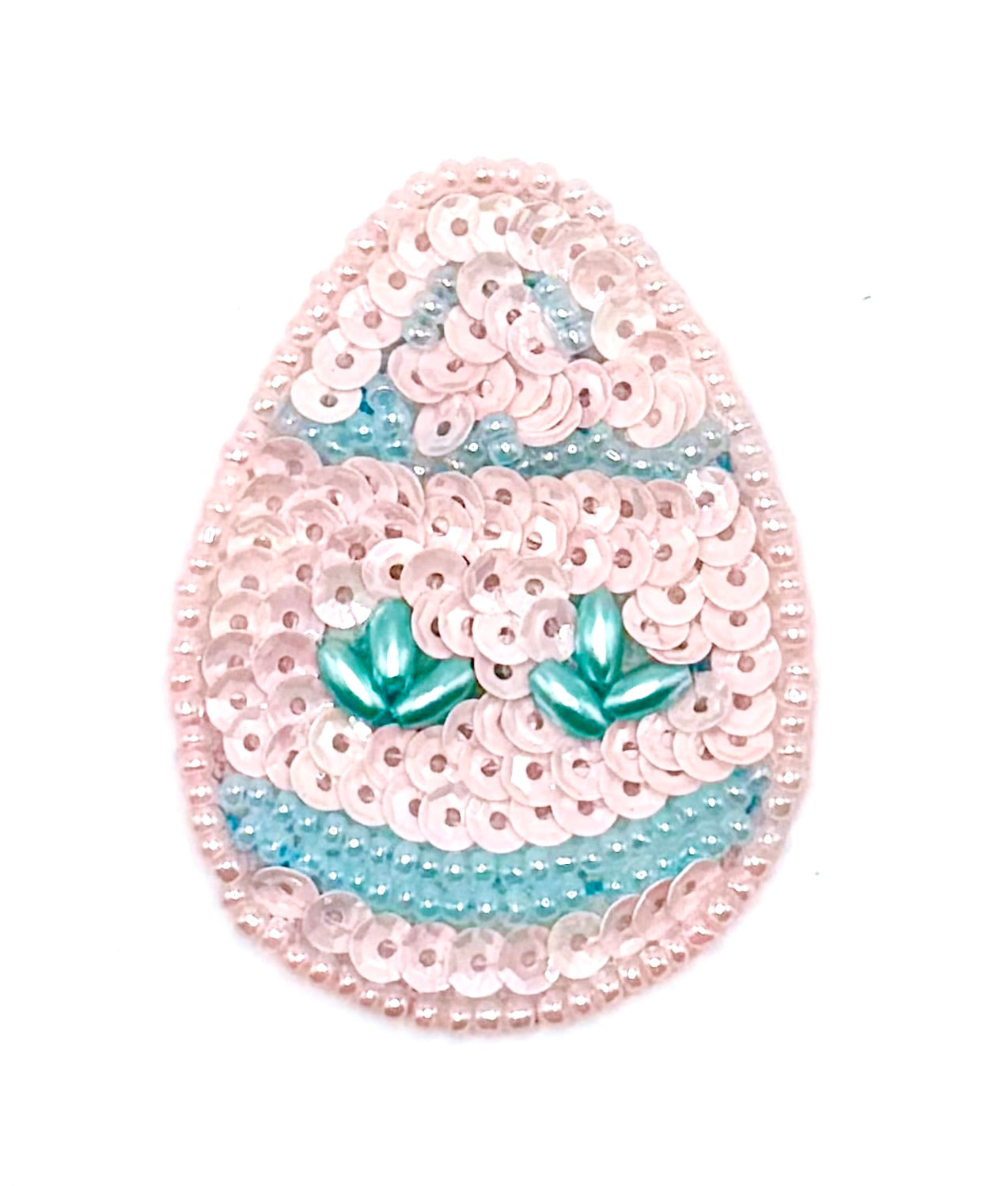 Sequined egg-shaped object with pink and blue patterns on a white background