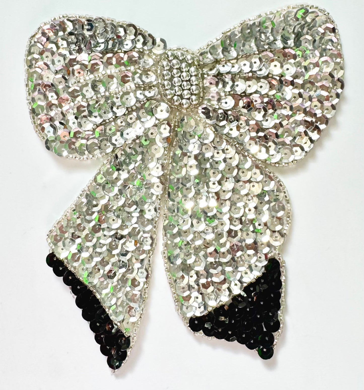 Silver sequin bow with black accents on a white background