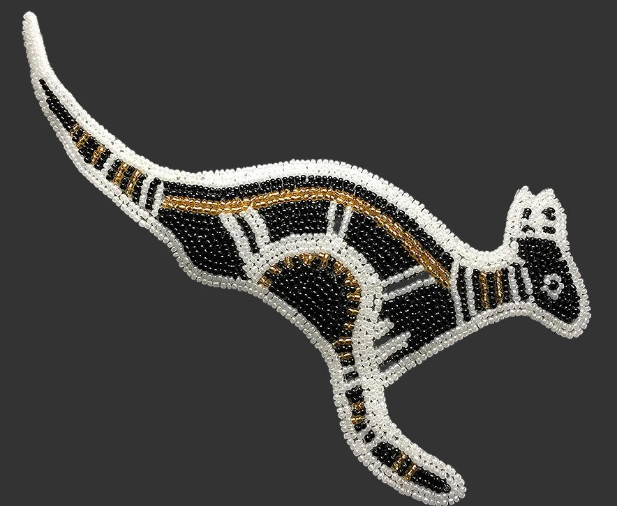 Decorative patch of a kangaroo with black, gold, and white beads on a dark background