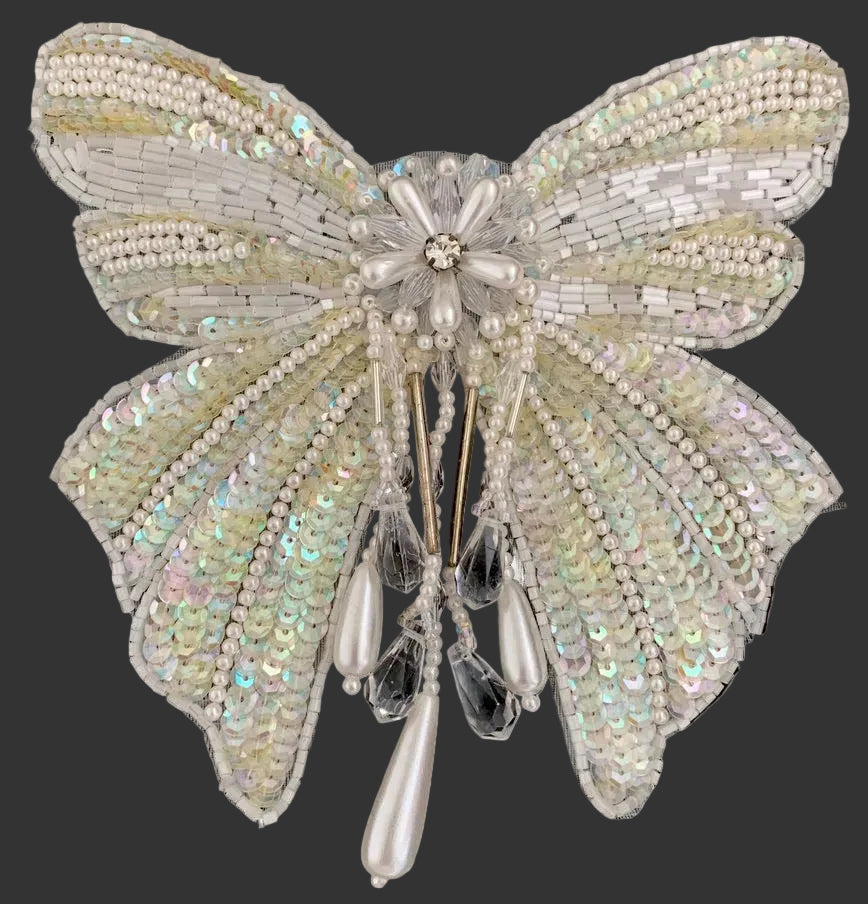 Sequin bow-shaped patch with bead and pearl details on a dark background