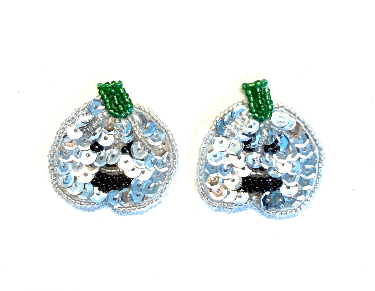 Two identical sequined pumpkin embellishments on a plain white background. Each pumpkin features light blue and silver sequins, a black sequined face, and a green beaded stem.