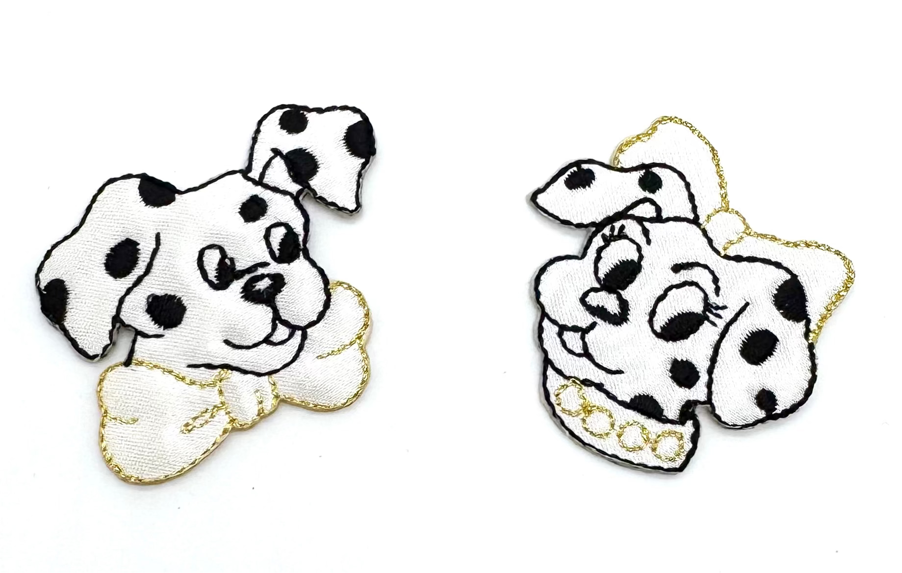 Two embroidered patches of Dalmatian dogs with black spots on a white background.