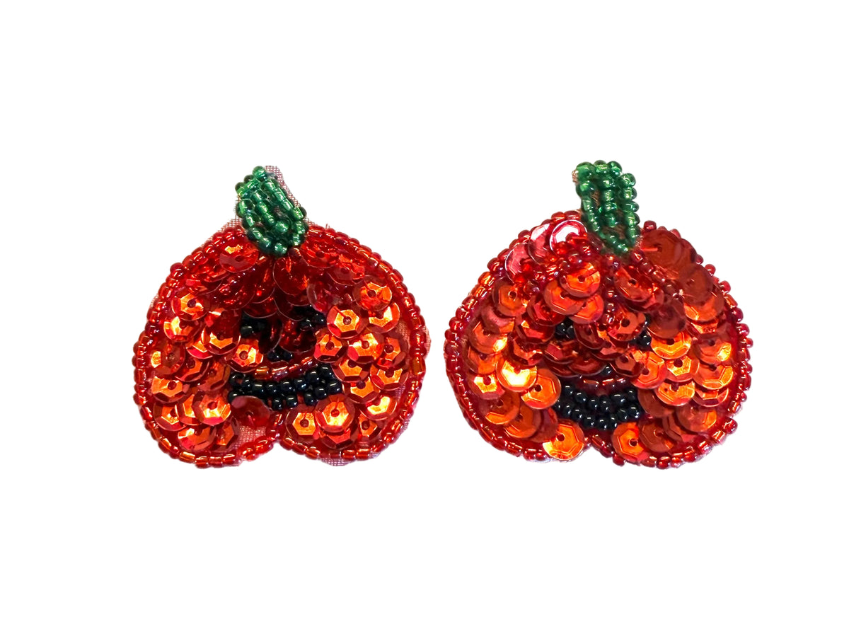 A pair of red sequined pumpkin-shaped patches with green beaded stems, displayed on a plain white background.