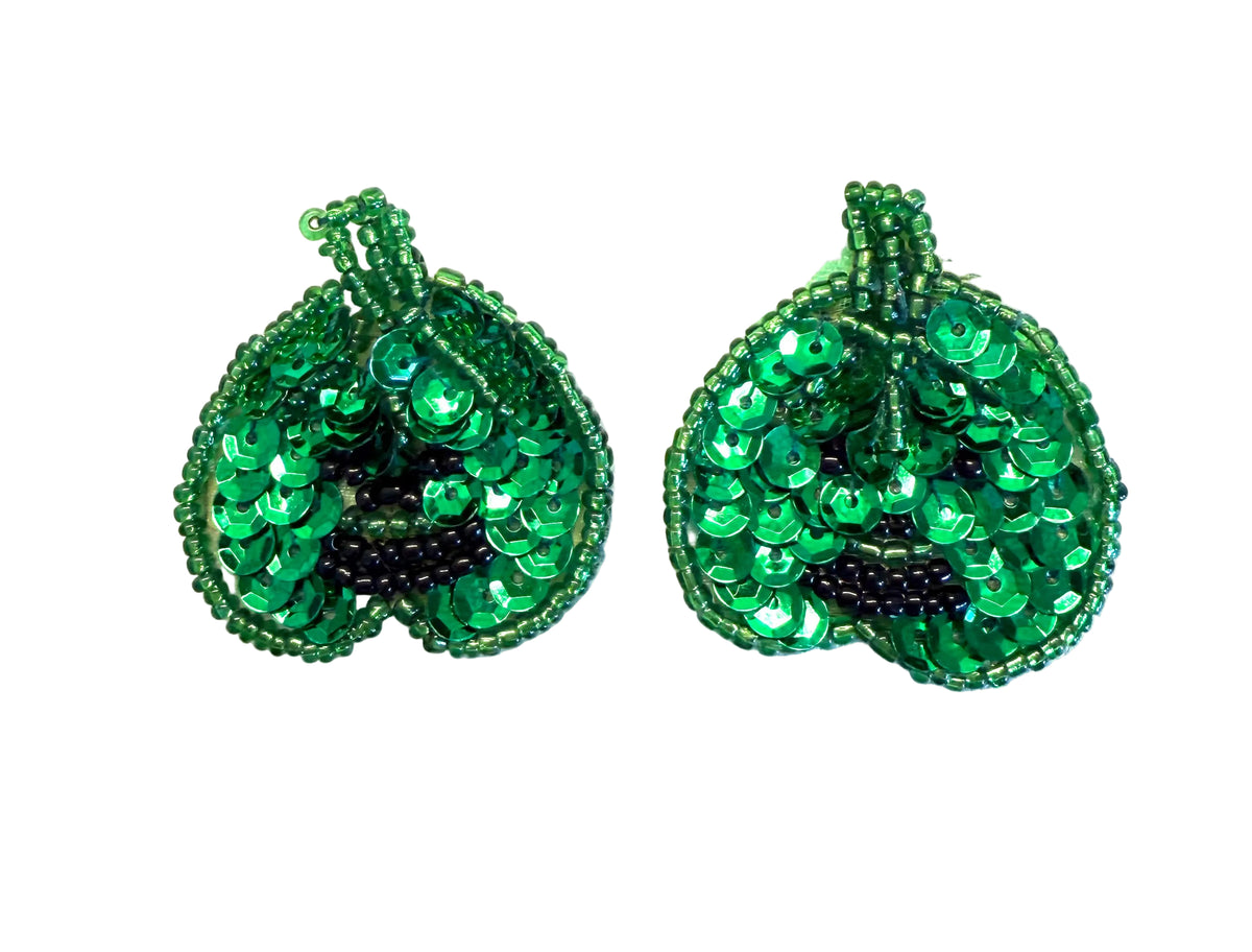 A pair of green beaded and sequined pumpkin embellishments on a plain white background.