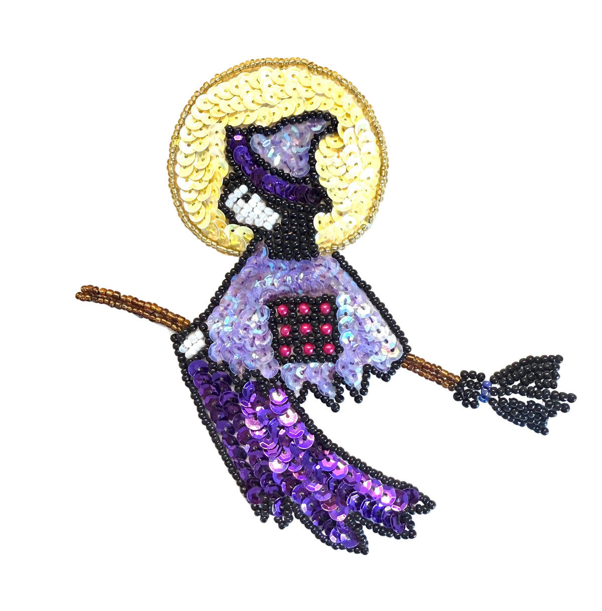 A beaded witch figure on a broomstick with a light yellow moon, purple hat and skirt, lavender dress, and black details, photographed on a plain white background.