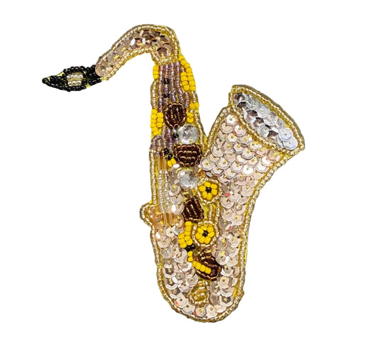 A decorative saxophone-shaped embellished patch featuring gold sequins, yellow and brown beads, and small pearl-like accents on a white background.