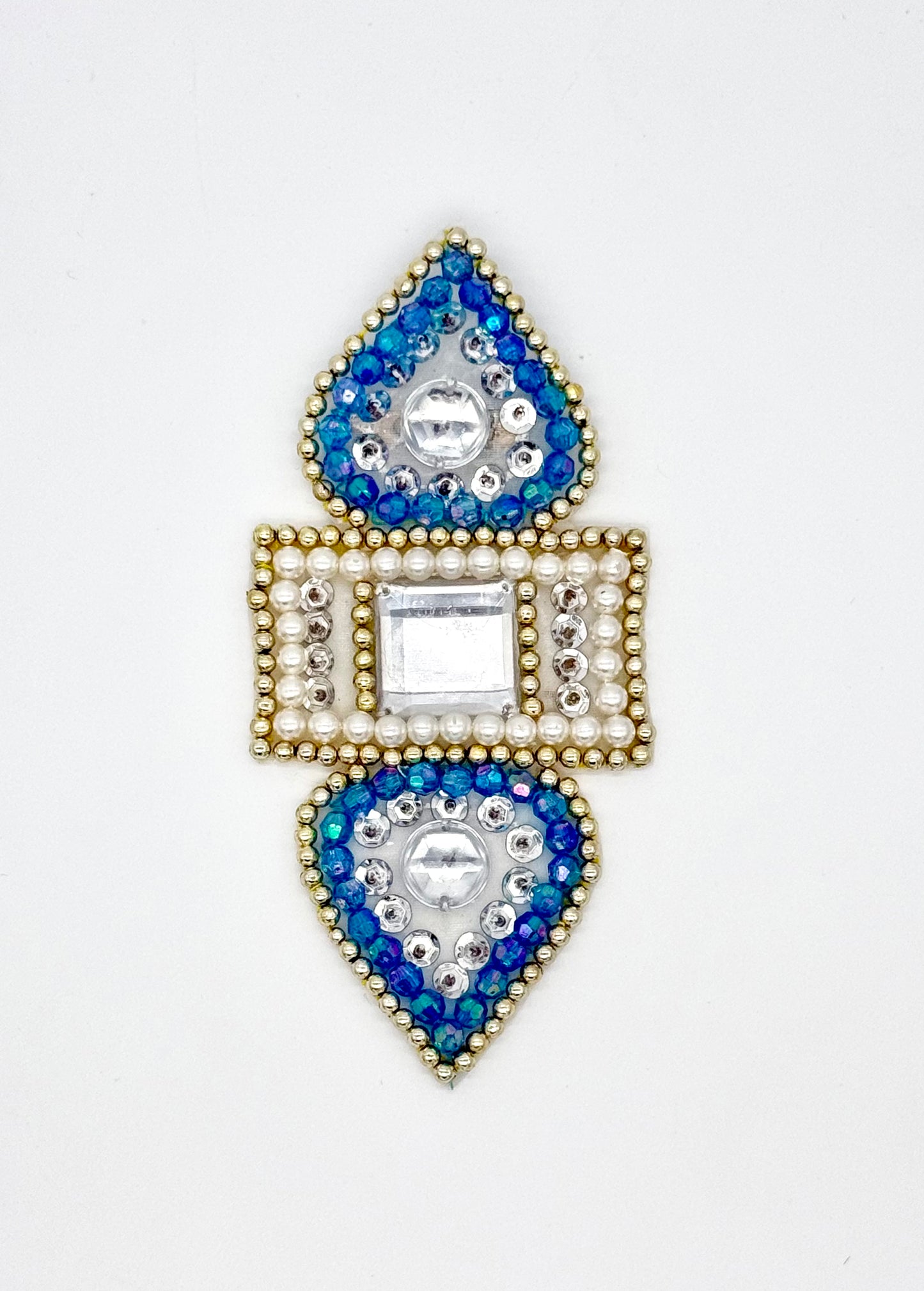 Decorative appliqué with blue and gold gemstones on a white background