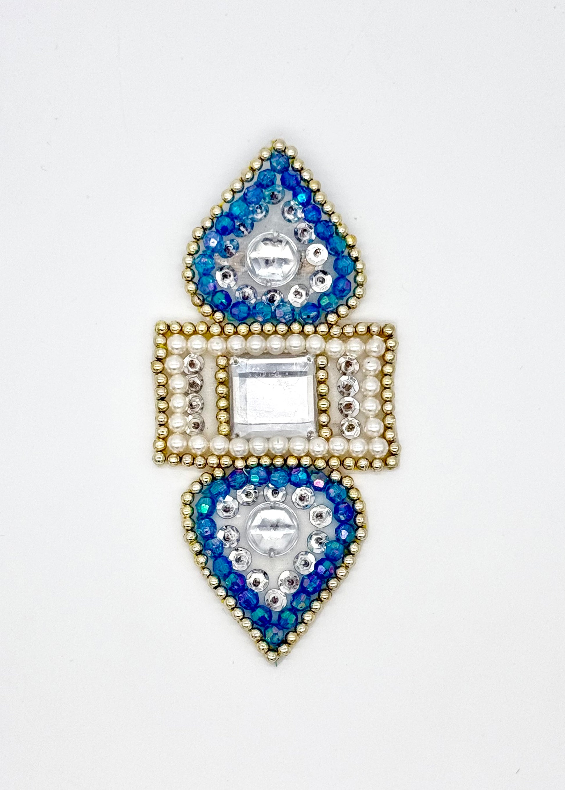 Decorative appliqué with blue and gold gemstones on a white background