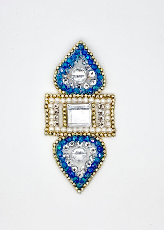 Decorative appliqué with blue and gold gemstones on a white background