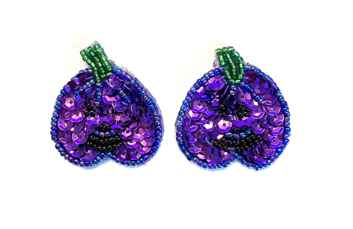 Sequin and bead pumpkin pair with purple sequins, a green bead stem and black bead eyes and mouth on a white background.