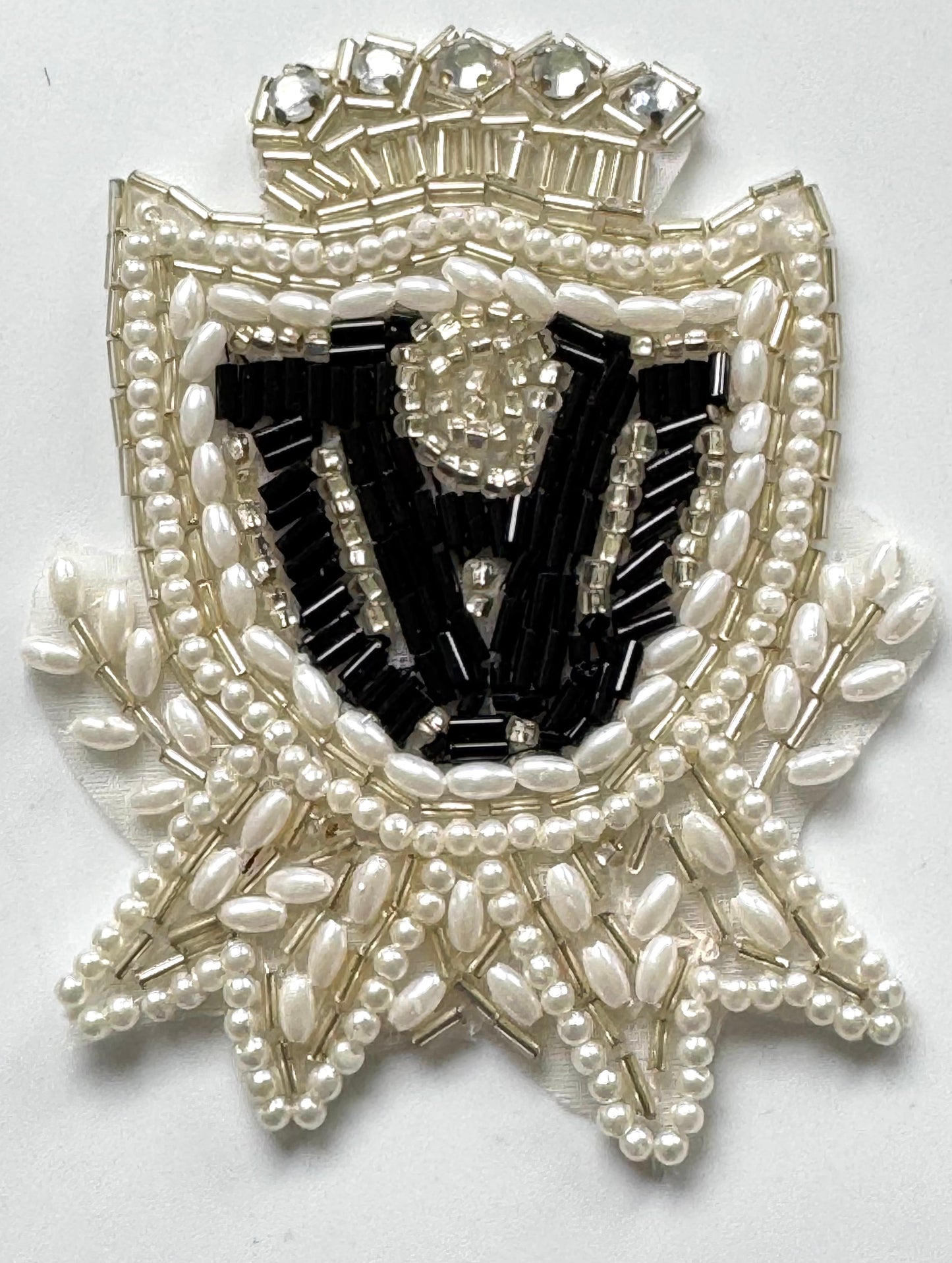 Escudo con perlas y pedrería negras, blancas y plateadas de 3.5" x 2.5"