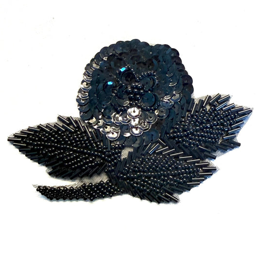 Bring floral sparkle to your next design with this black sequin flower appliqué. Bugle, glass, and pearl beads add textured detail to the shimmering flower motif.