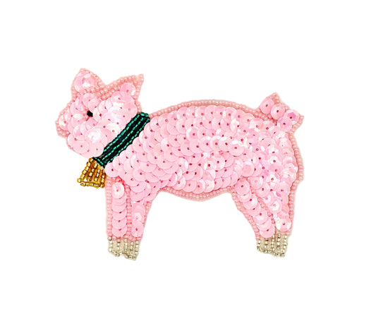 Sequined pink pig with a turquoise and gold bow on a white background