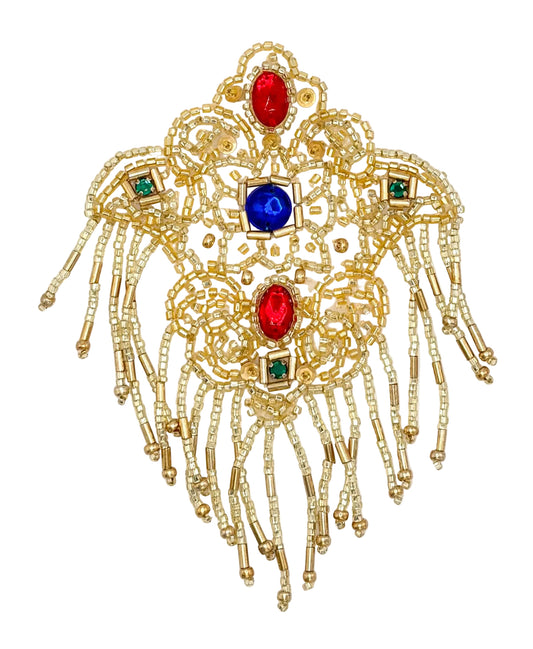 An ornate gold-toned beaded decorative piece with dangling fringe, featuring red and blue gemstone accents and small green square accents, shown on a plain white background.