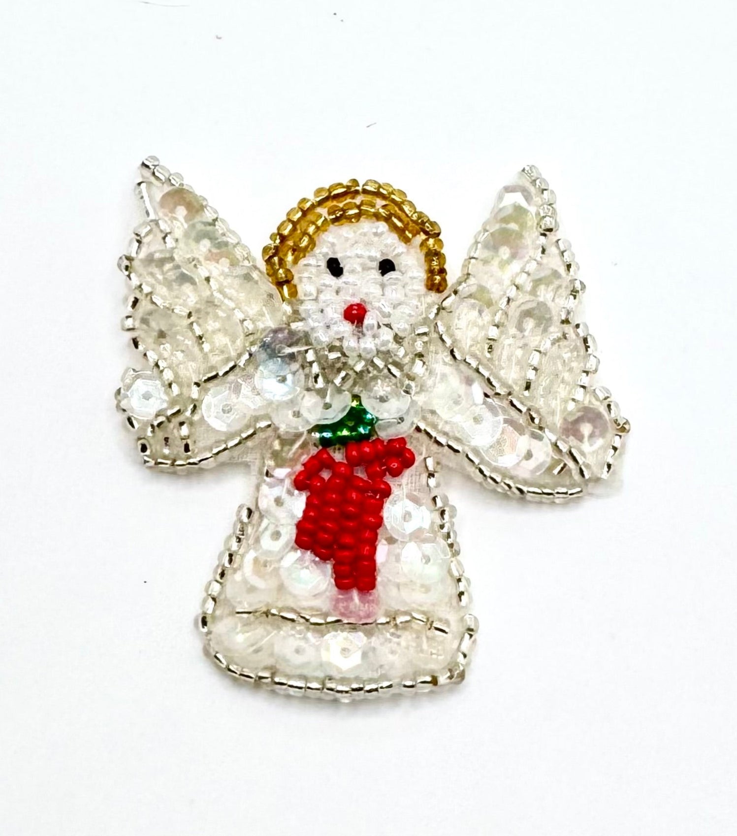 A handcrafted beaded Christmas angel appliqué featuring a iridescent sequin dress, red beaded flowers, gold beaded hair, and silver beaded wings on a plain white background.