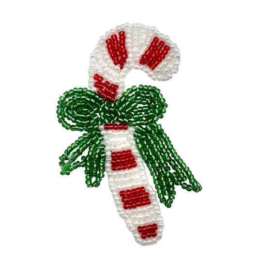 A beaded candy cane ornament or patch featuring a white cane with red stripes and a green bow, crafted from small seed beads on a plain white background.