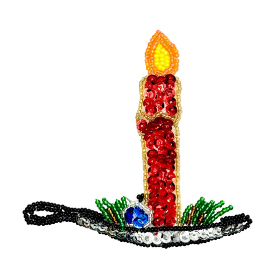 A decorative candle-shaped embellishment or patch with red sequins, a yellow and orange flame, green and silver beaded accents, and a blue sequin accent, shown on a plain white background.