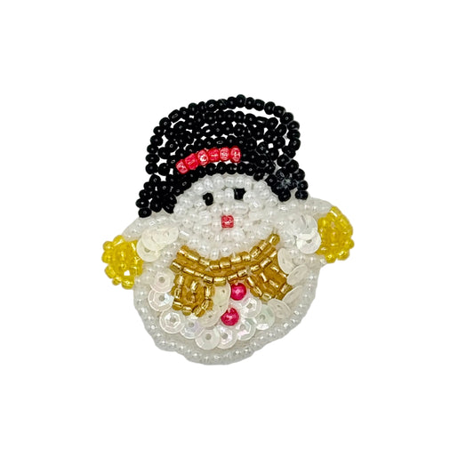 A handcrafted beaded snowman patch featuring black seed beads for a hat, white sequins and beads for the body, gold beads for a scarf, and small red beads for facial details and hat accents, set against a plain light gray background.