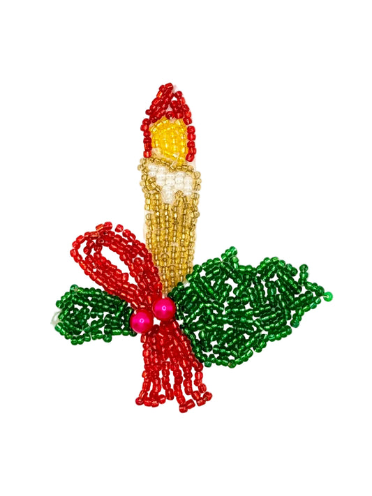 A beaded Christmas appliqué  featuring a candle with a red flame, a gold beaded body, green holly leaves, and a red bow with pink beads, shown on a plain white background.