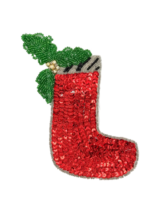 A Christmas stocking sequin patch with red sequins, green holly leaves, small gold beads, and a black and white striped cuff, shown on a plain white background.