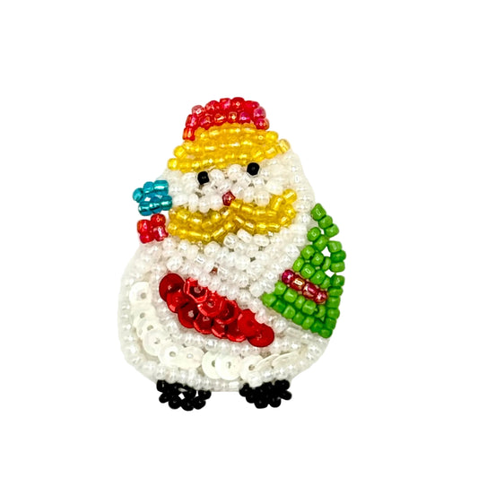 A handcrafted Christmas ornament shaped like a Santa Claus figure made from sequins and glass beads, featuring a white body, red hat and coat, yellow scarf, green tree, and small black and blue accents, shown on a plain white background.