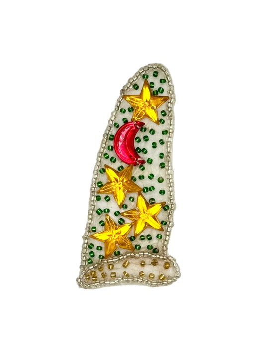 A Christmas-themed sequin and bead patch shaped like a stocking or sleeping hat, featuring gold stars, a red crescent moon, and green beads on a white background.