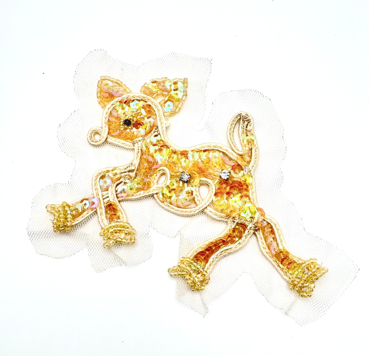 An embroidered patch of a running fawn made from iridescent gold sequins, outlined in gold thread, and decorated with small rhinestones, shown on a white background.