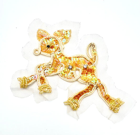 An embroidered patch of a running fawn made from iridescent gold sequins, outlined in gold thread, and decorated with small rhinestones, shown on a white background.