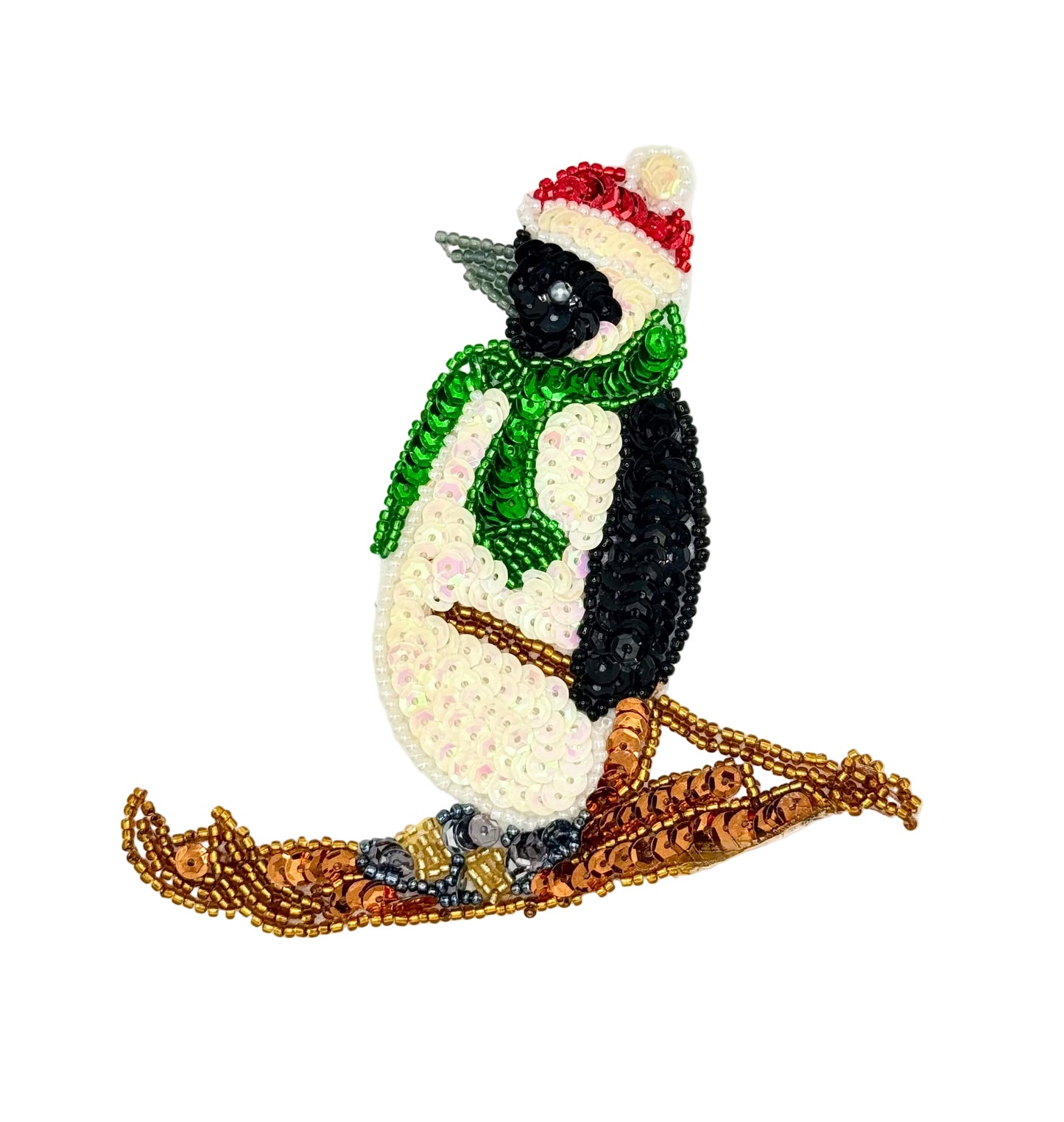 A decorative penguin skiing patch or applique featuring a black-and-white body, a green scarf, a red-and-white hat  shown on a plain white background.