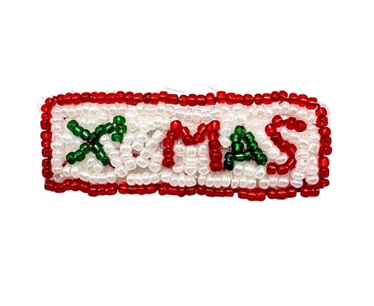 A rectangular beaded patch spelling 'X-MAS' with a red border, white beads, and red and green lettering, shown on a plain white background.