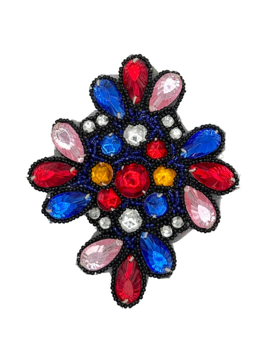 A circular beaded patch featuring a floral or snowflake-like design with red, blue, pink, yellow, and clear rhinestones, outlined in black beads, on a white background.