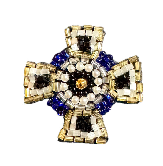 A handmade beaded cross pendant featuring a central gold circle surrounded by white pearl-like beads, a dark blue outer ring, and gold, white, and black striped sections on the arms, set against a plain white background.