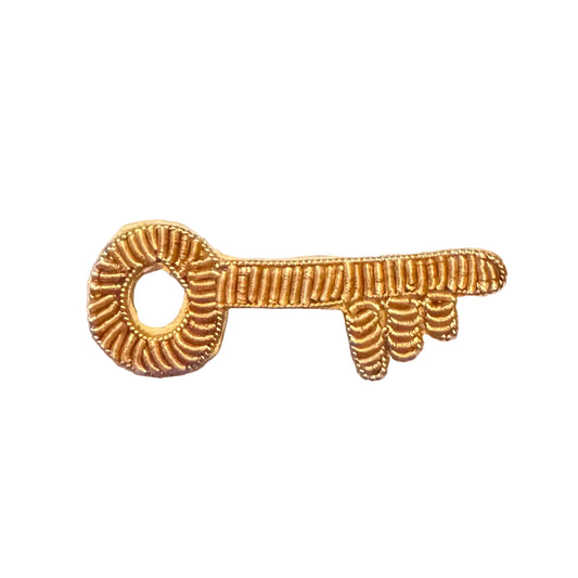 A small embroidered key-shaped patch in a metallic  bullion thread gold color, displayed on a white background.