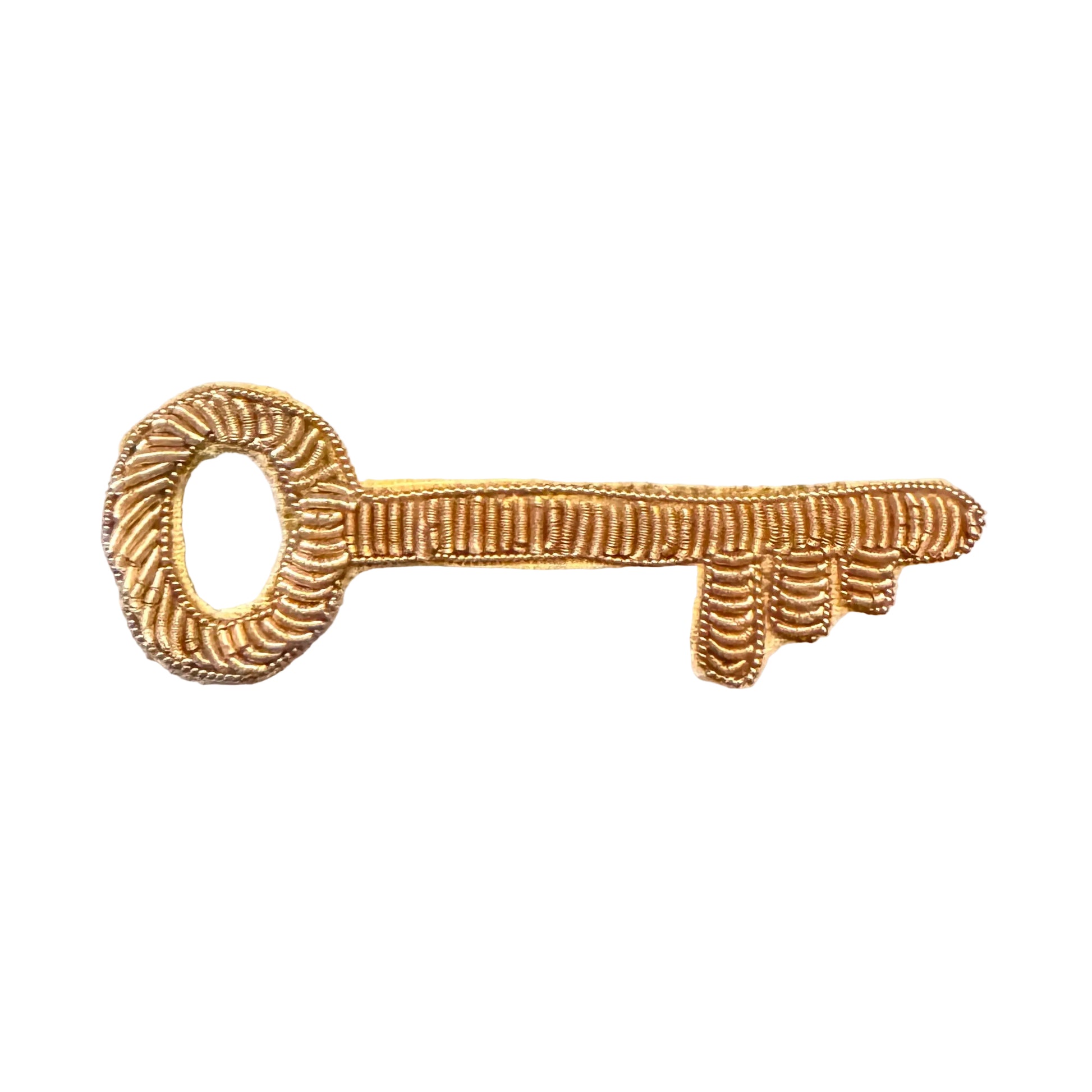 A small gold-colored embroidered patch shaped like a decorative key, featuring textured, raised stitching on white background.
