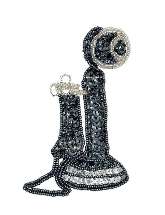 A decorative embroidered patch shaped like an old fashion phone, made from gray and silver sequins and beadwork on a plain white background.