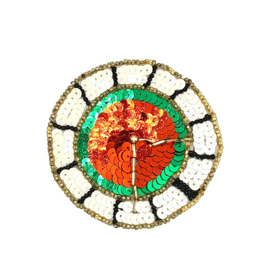 A circular sequined wall clock with a colorful design. The center features red orange sequins, surrounded by green sequins, and the outer ring has white, black, and gold sequins.