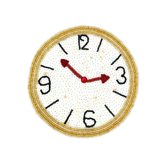 A circular clock face applique with a beaded silver and gold border, black Arabic numerals, and red hands on a white background.