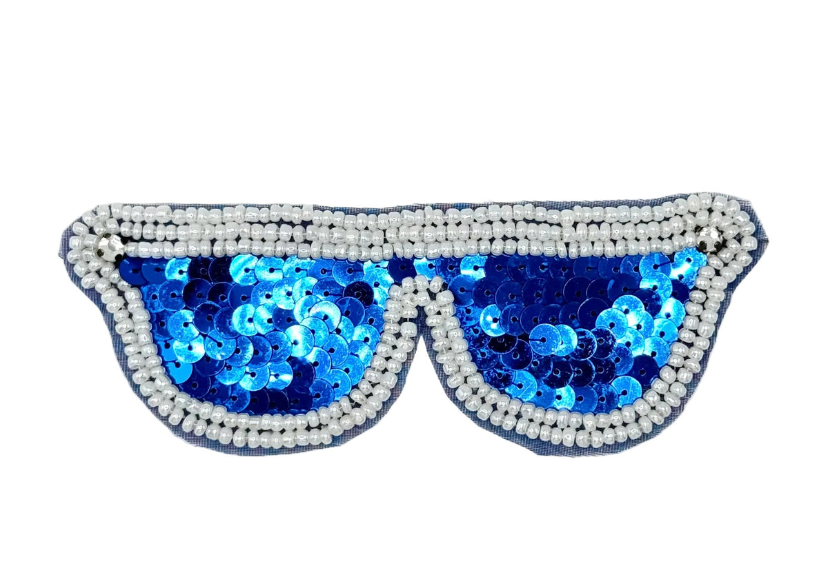 A novelty costume accessory shaped like sunglasses, featuring bright blue sequins in the lenses and a border of white beads and rhinestones on a white background.