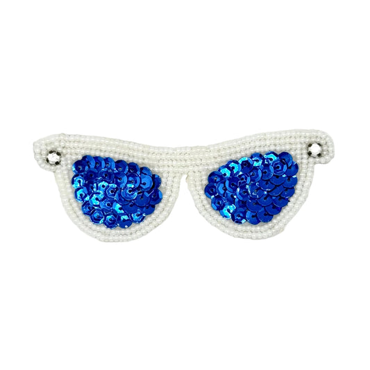 A pair of novelty sunglasses with bright blue sequined lenses and white beaded frames with rhinestones set against a plain white background.
