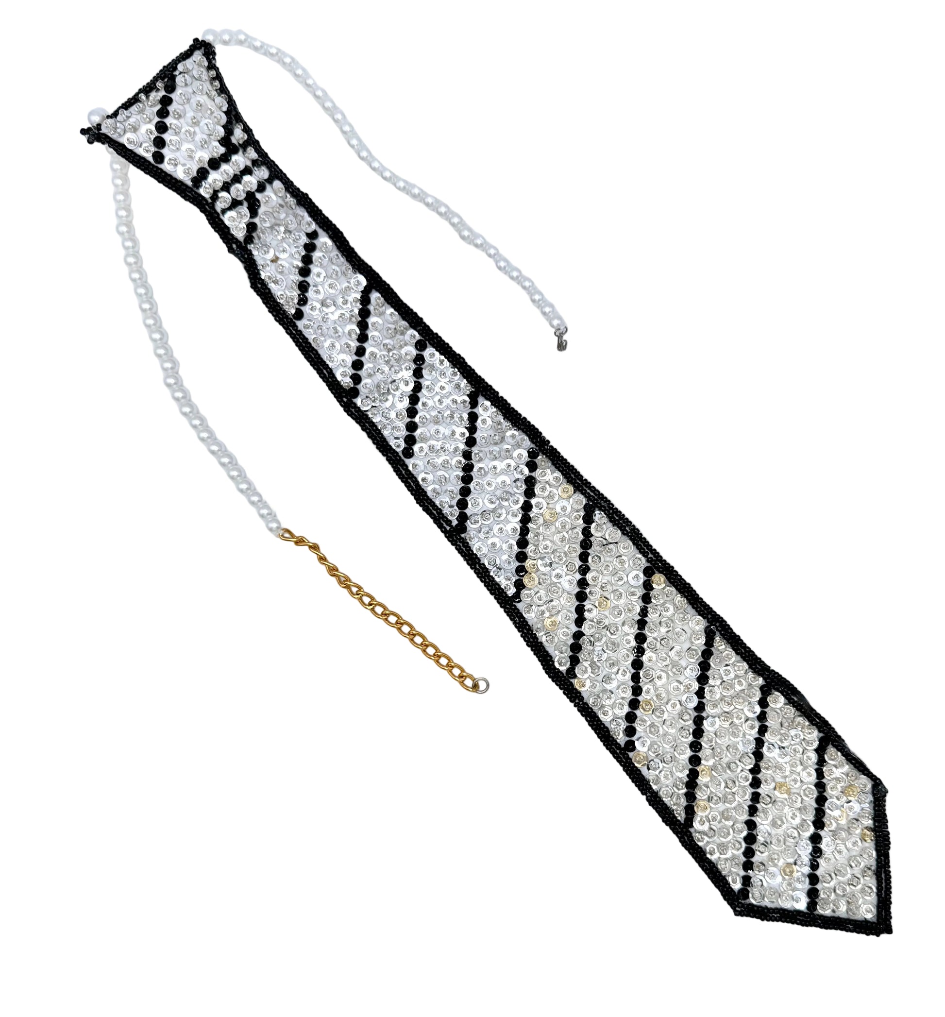 A novelty necktie accessory made of white faux pearls and black and white sequins and beads, with a gold chain extender, displayed on a plain white background.