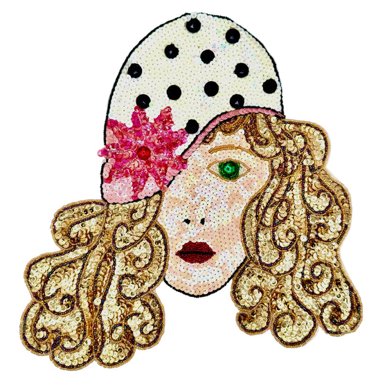 A stylized sequined portrait of a woman's face with curly blonde hair, a white hat with black polka dots, and a pink flower accent, shown on a plain white background.