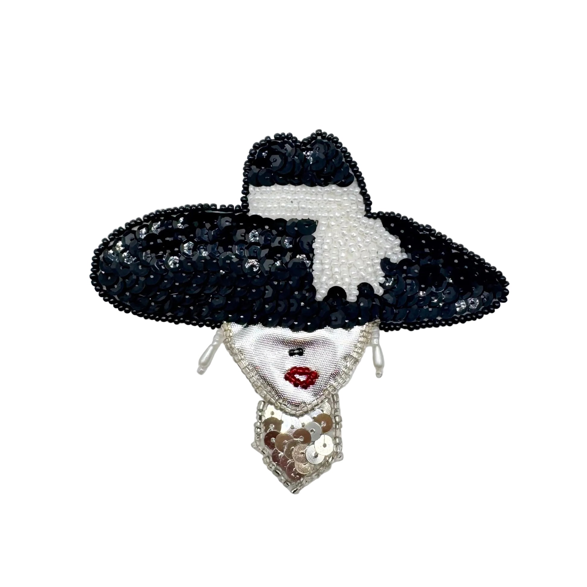 A decorative sequin and beaded patch shaped like a stylized face wearing a large black hat with a white band, a white bow, and dangling earrings. The face has red lip  and black nose detail, shown on a plain white background.